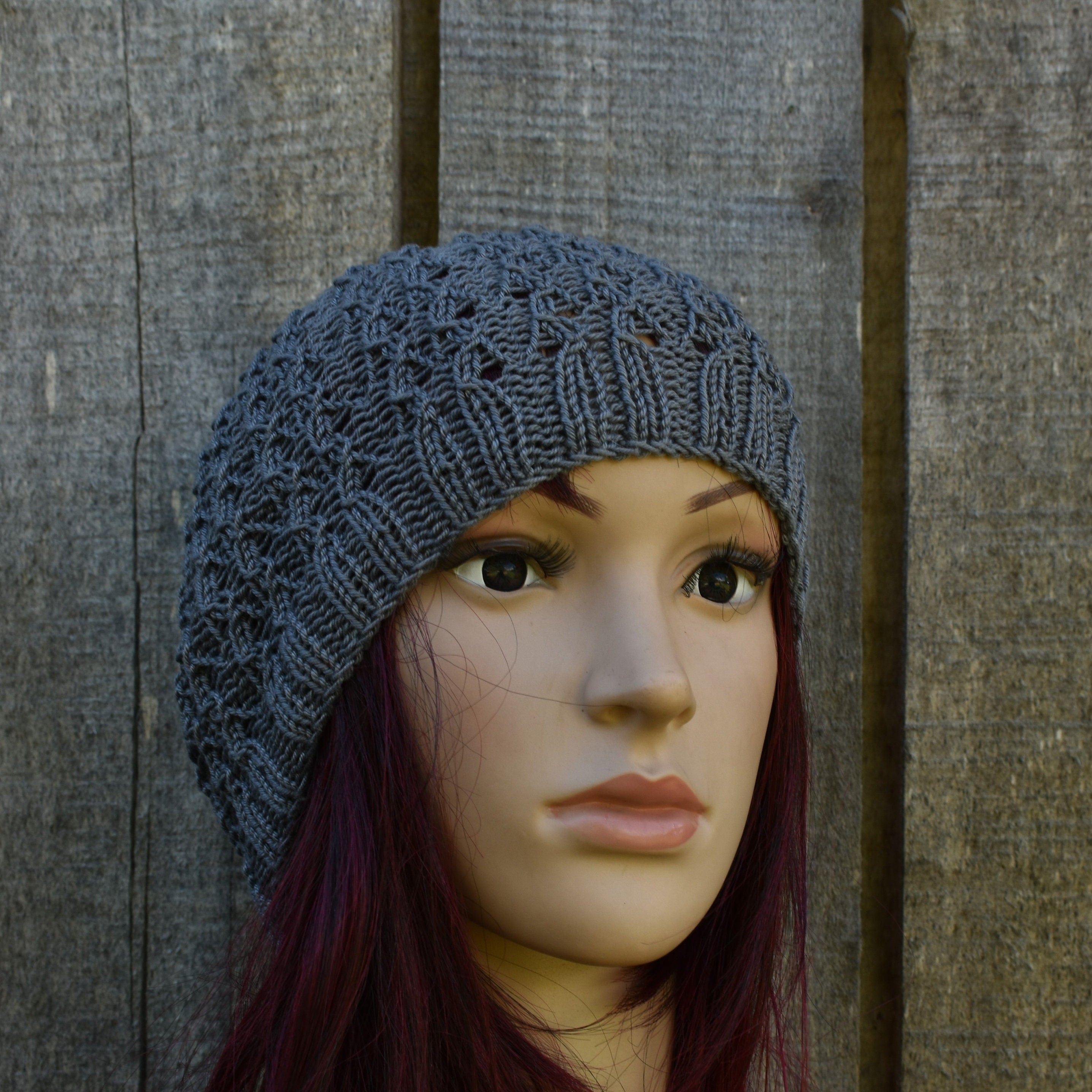 Mannequin head wearing a gray knit beanie against a wooden background
