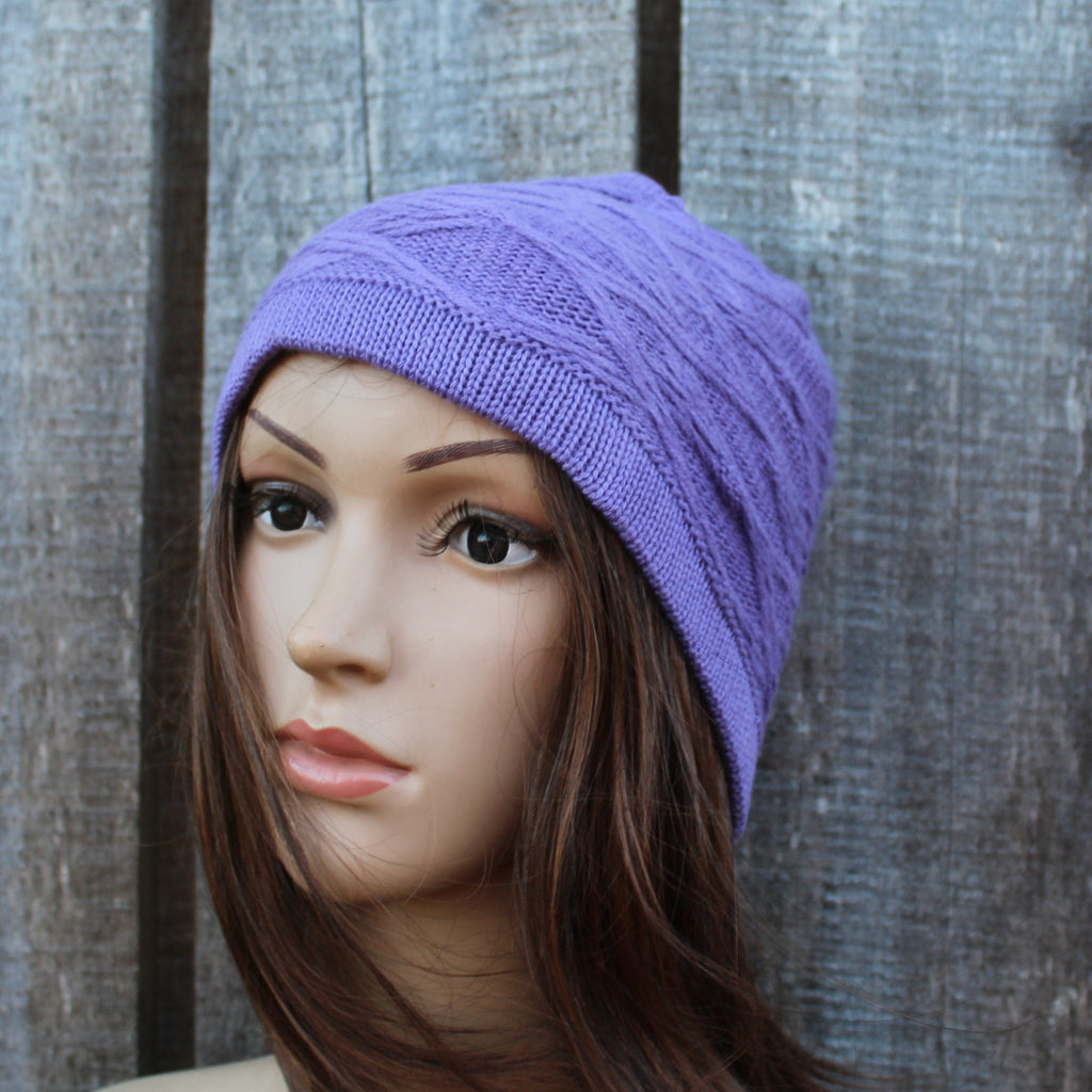 Mannequin head wearing a purple knit beanie against a wooden background