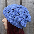 Blue knitted beanie worn by a person against a wooden background