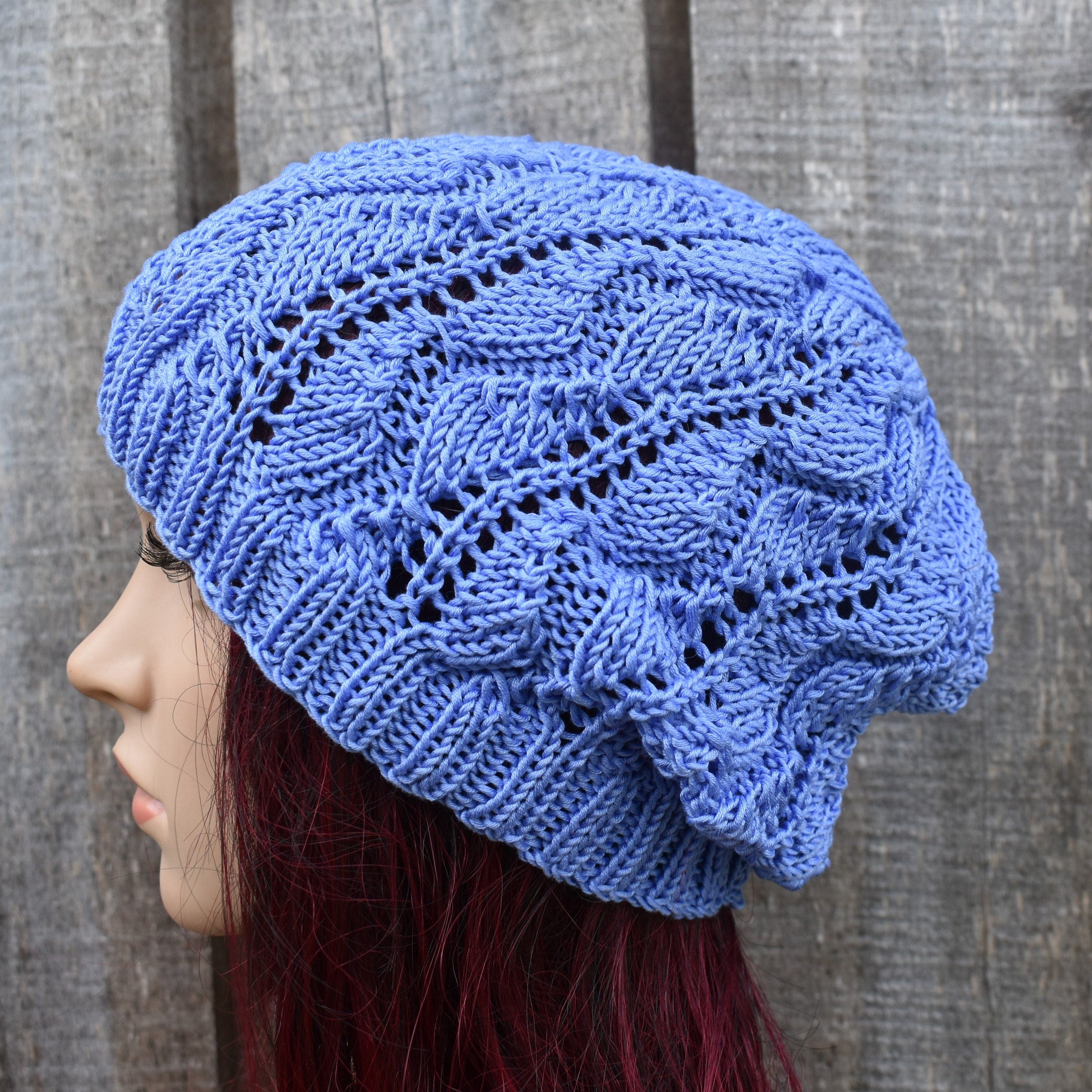 Blue knitted beanie worn by a person against a wooden background