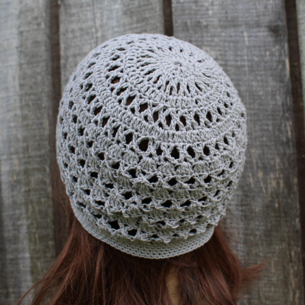 Crocheted gray beanie worn by a person with a wooden background