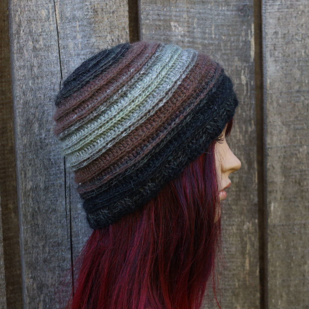 Person wearing a multicolored striped beanie against a wooden background