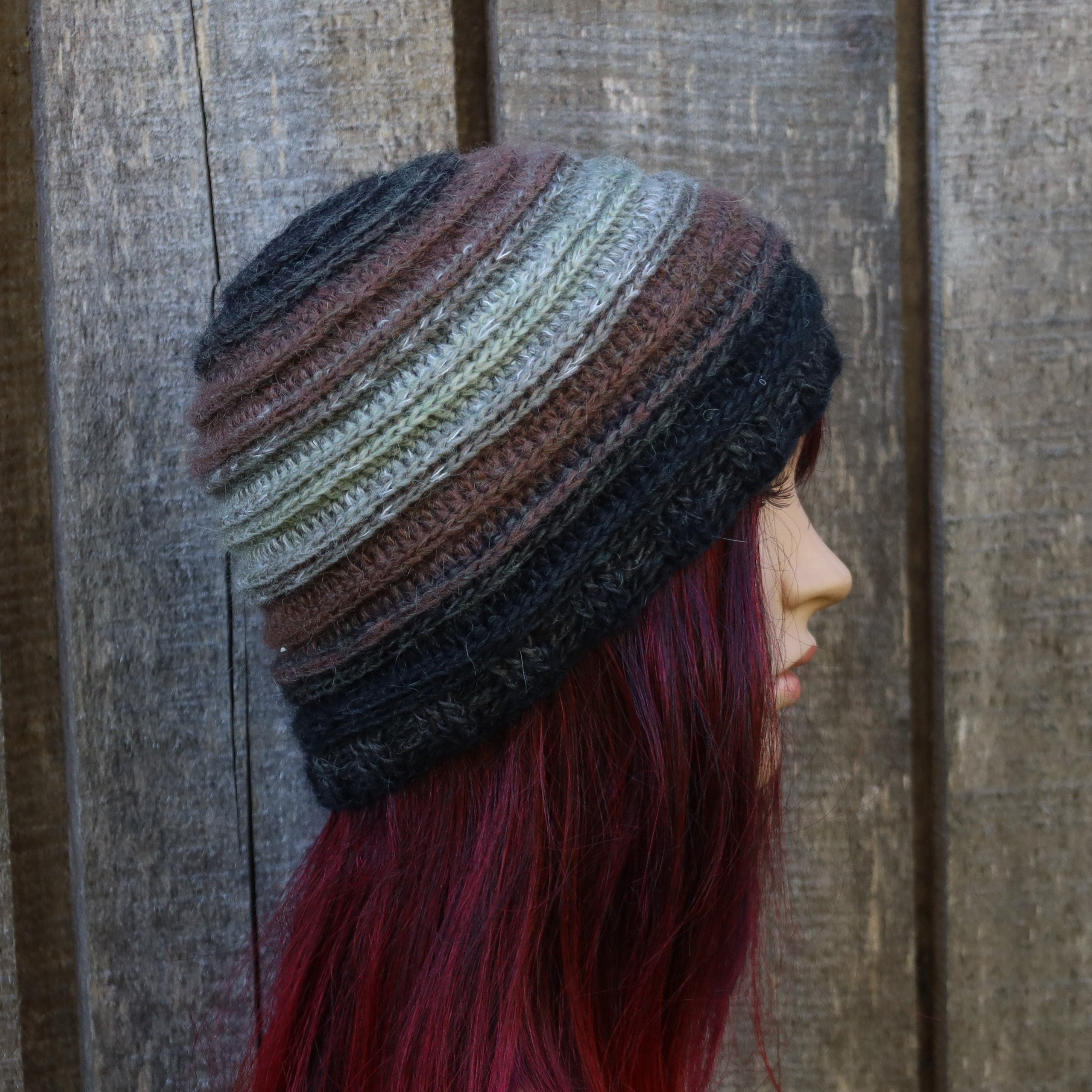 Person wearing a multicolored striped beanie against a wooden background