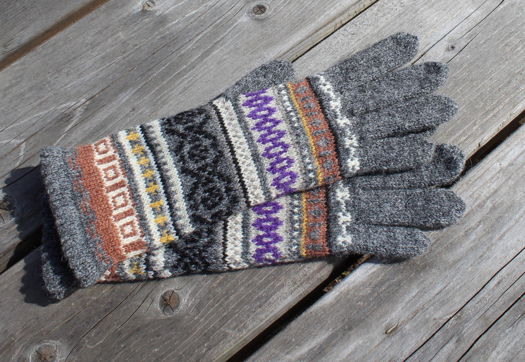Pair of gray gloves with colorful pattern on a wooden surface