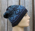 Blue and black patterned knit beanie on a mannequin head against a wooden background