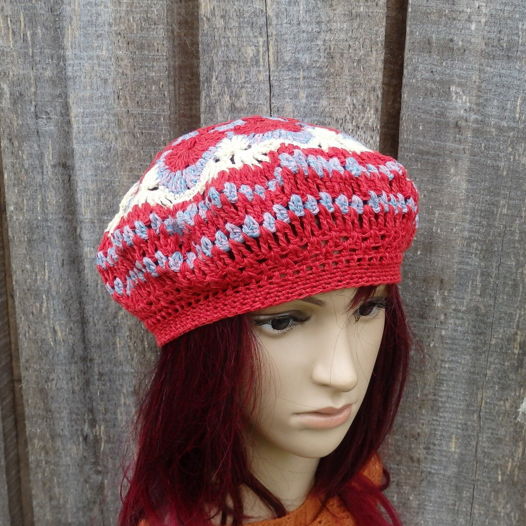Mannequin head wearing a red and white patterned crochet hat against a wooden background