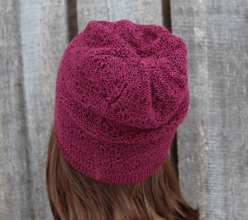 Maroon knitted beanie worn by a person with a neutral background