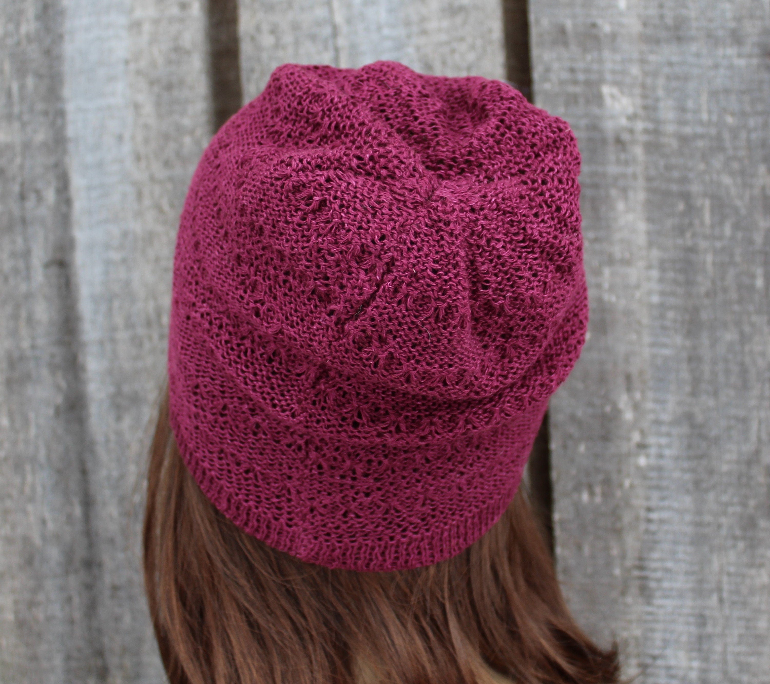 Maroon knitted beanie worn by a person with a neutral background