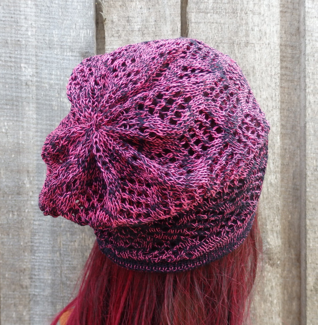 Knitted purple and pink beanie with fringe on a wooden background