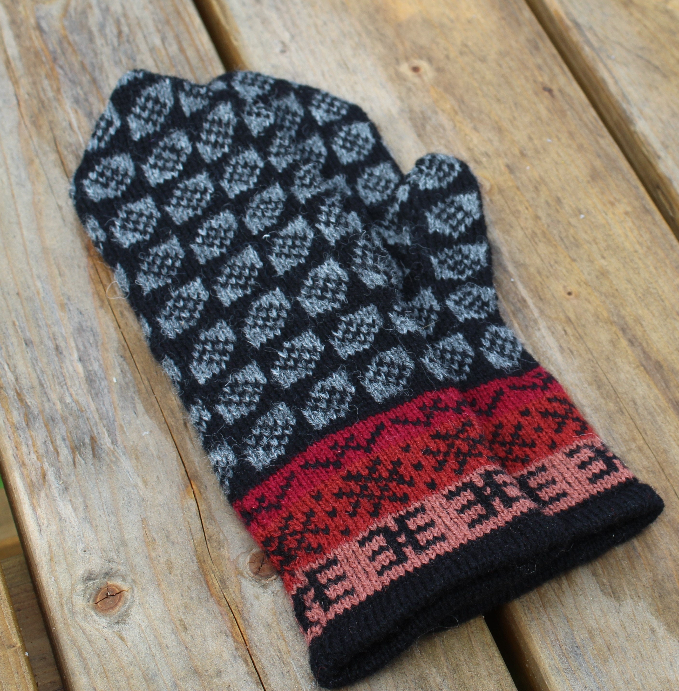 Knitted glove with geometric pattern on a wooden surface