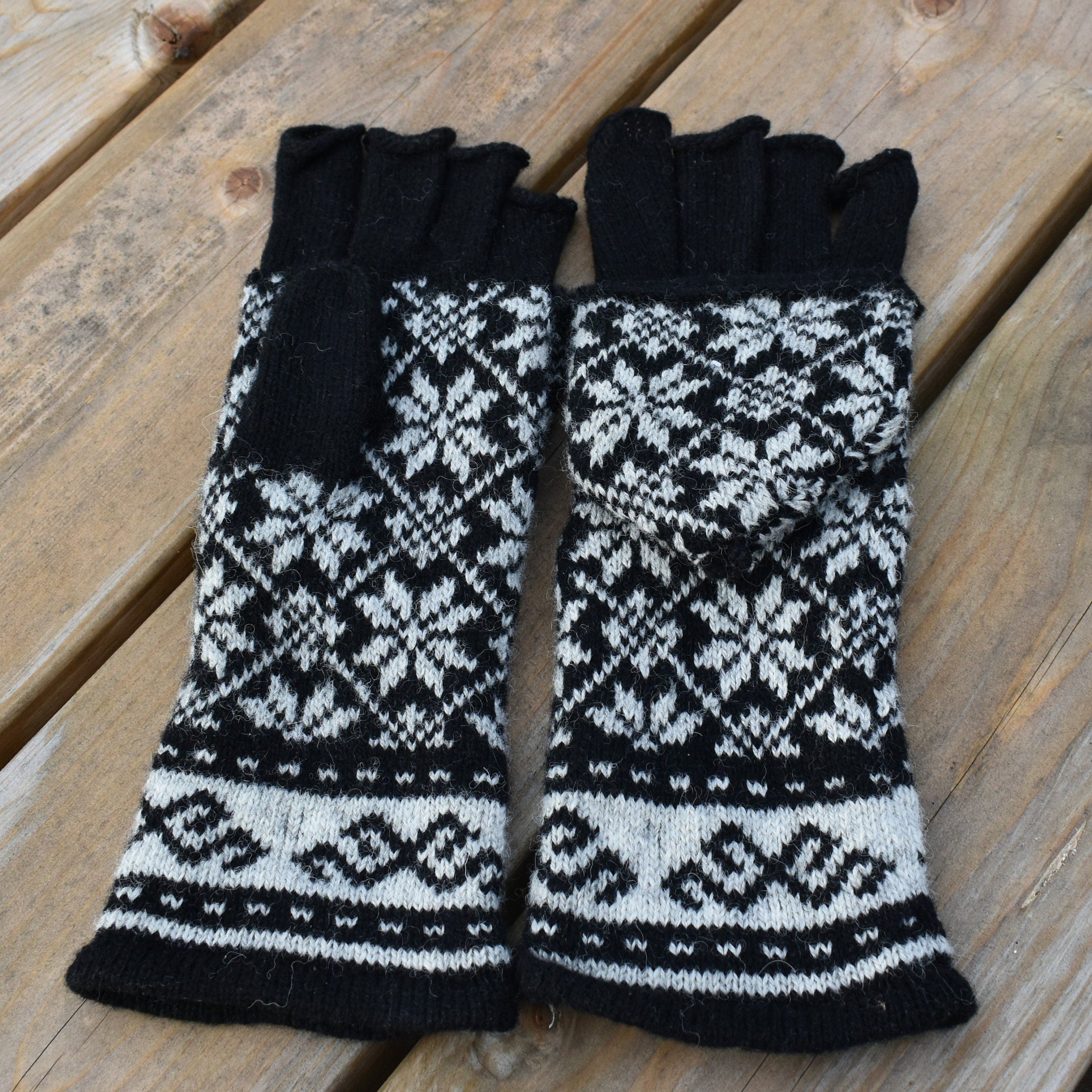 Pair of black and white patterned fingerless gloves on a wooden surface