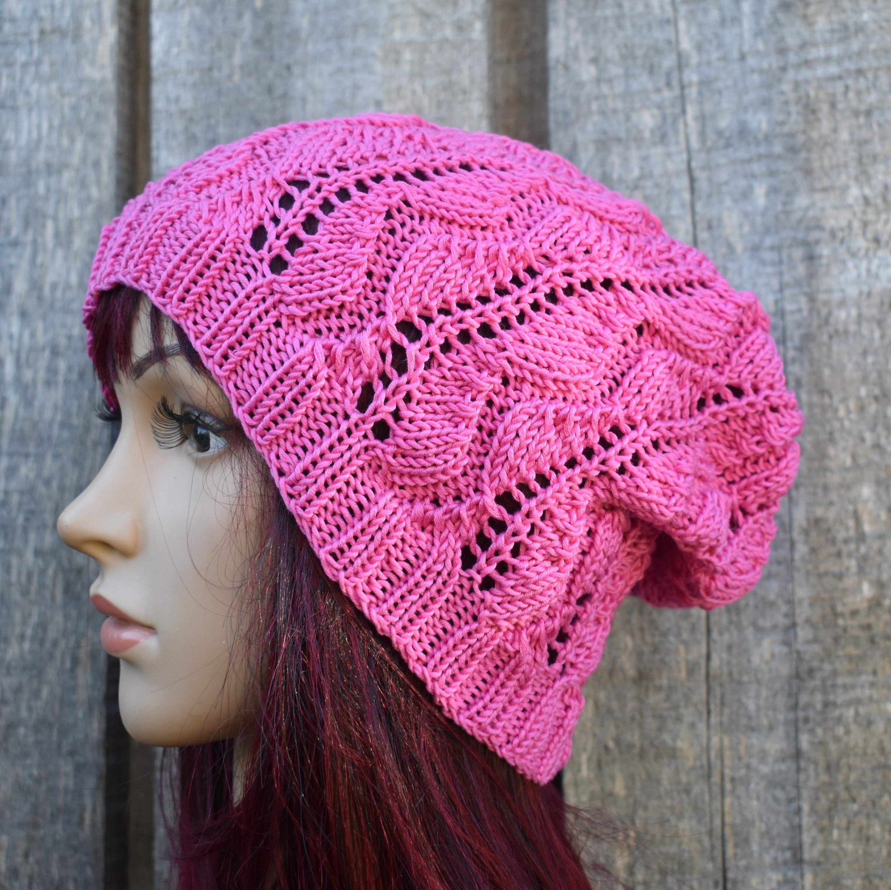 Pink knitted hat on a mannequin head against a wooden background