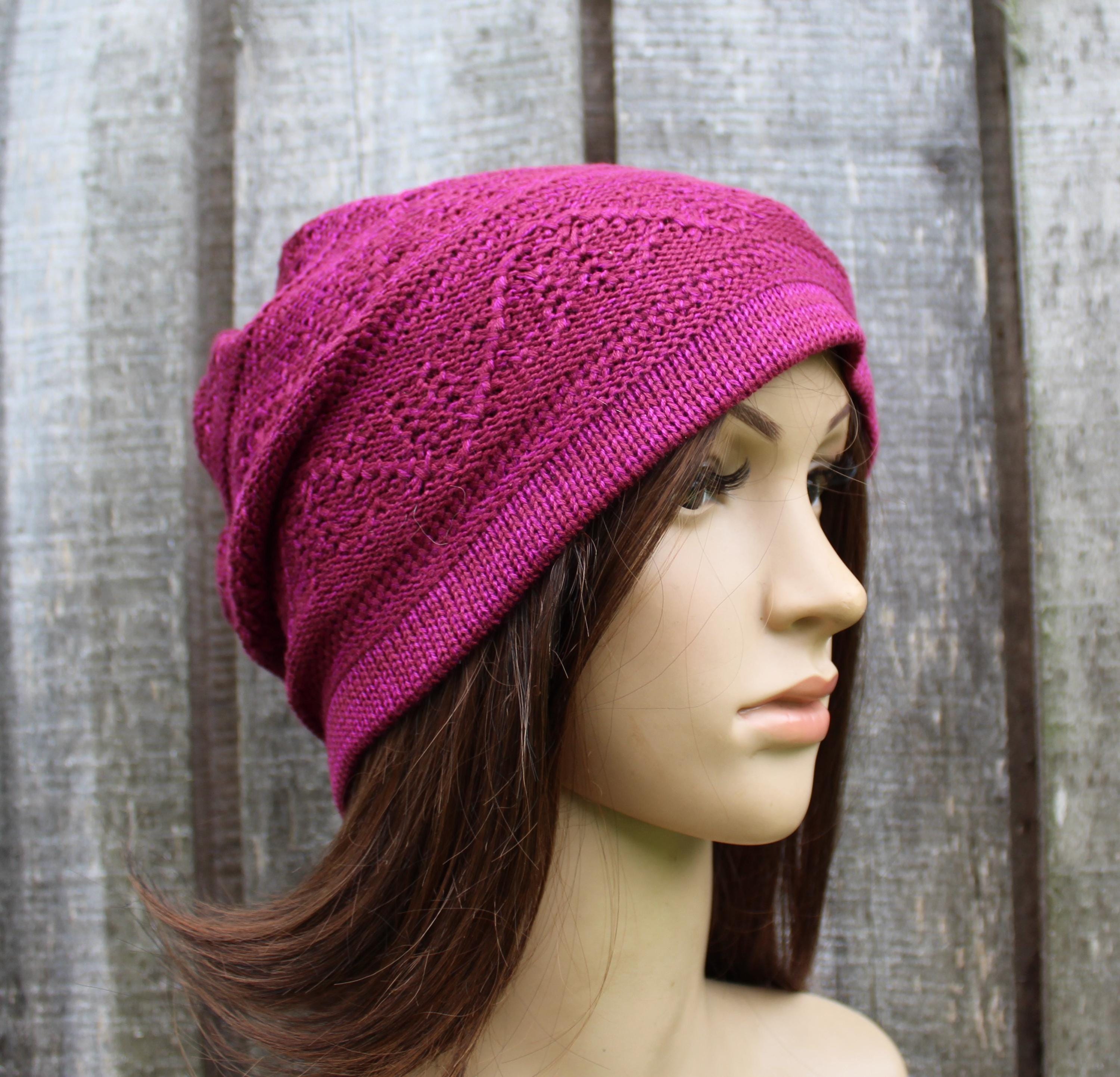 Mannequin head wearing a bright pink knitted beanie against a wooden background