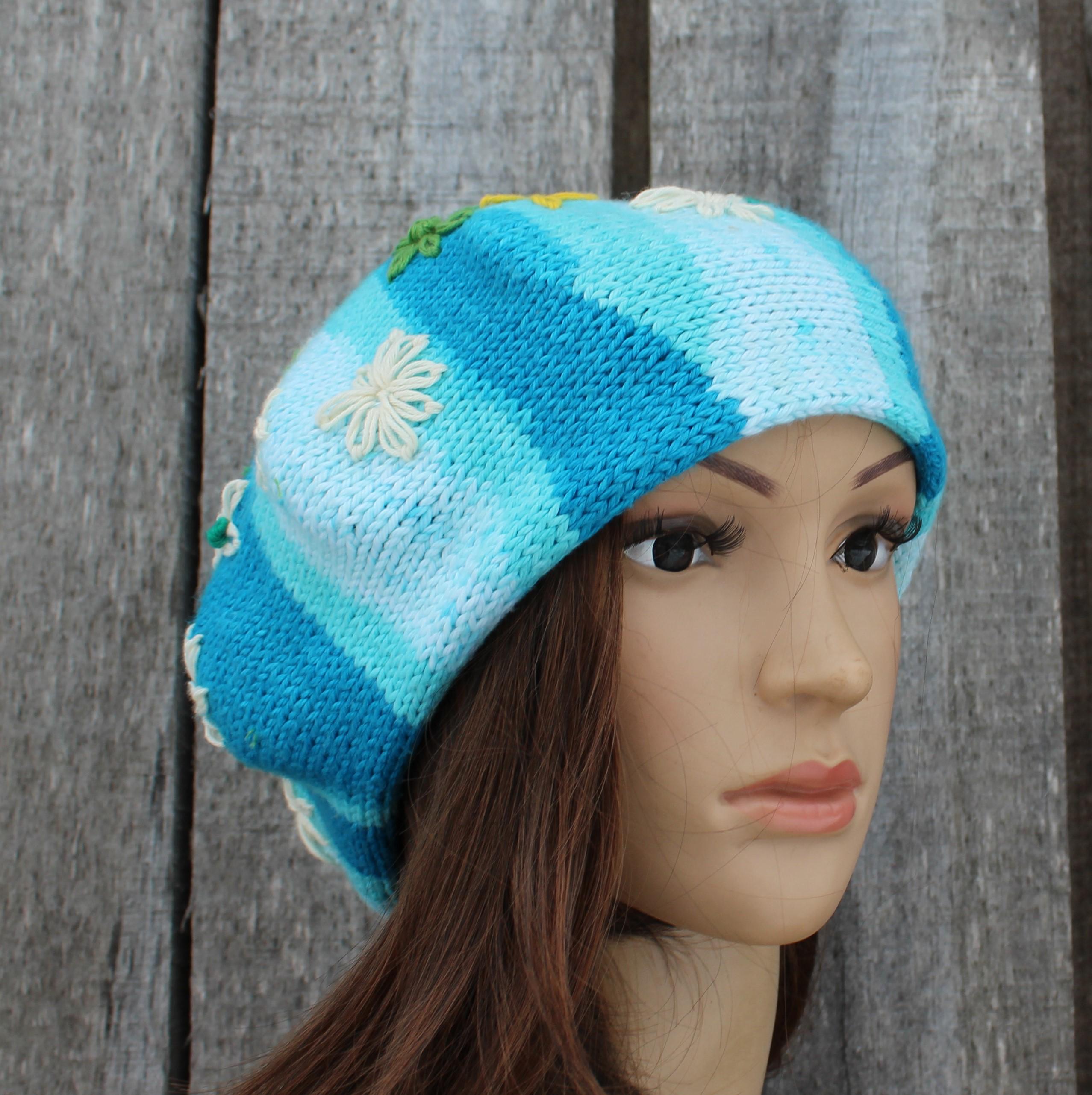 Knitted hat with blue and white stripes on a mannequin head against a wooden background