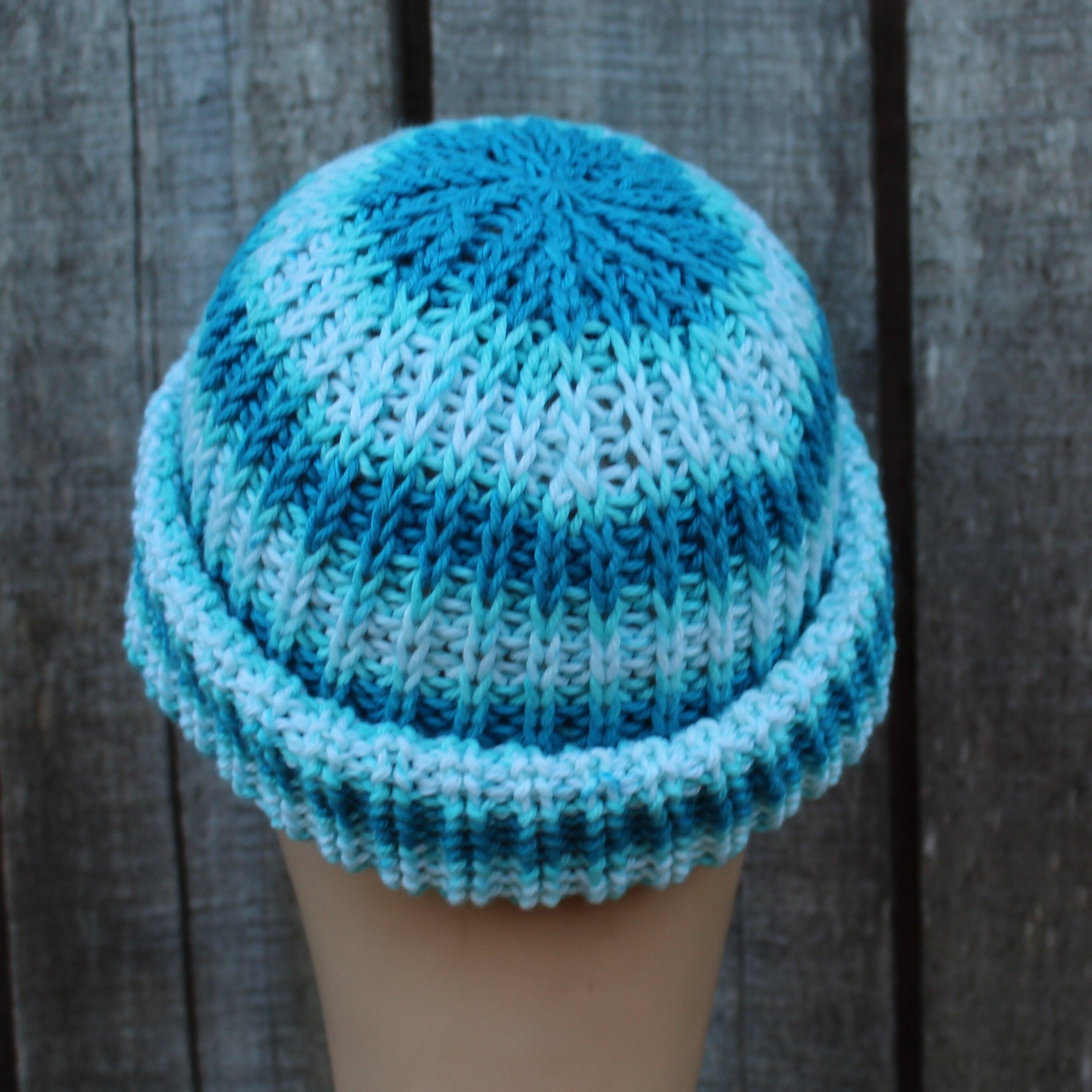 Knitted beanie with gradient blue pattern on a wooden surface