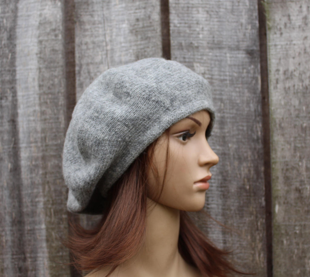 Mannequin head wearing a gray beret against a wooden background