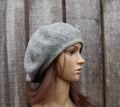 Mannequin head wearing a gray beret against a wooden background