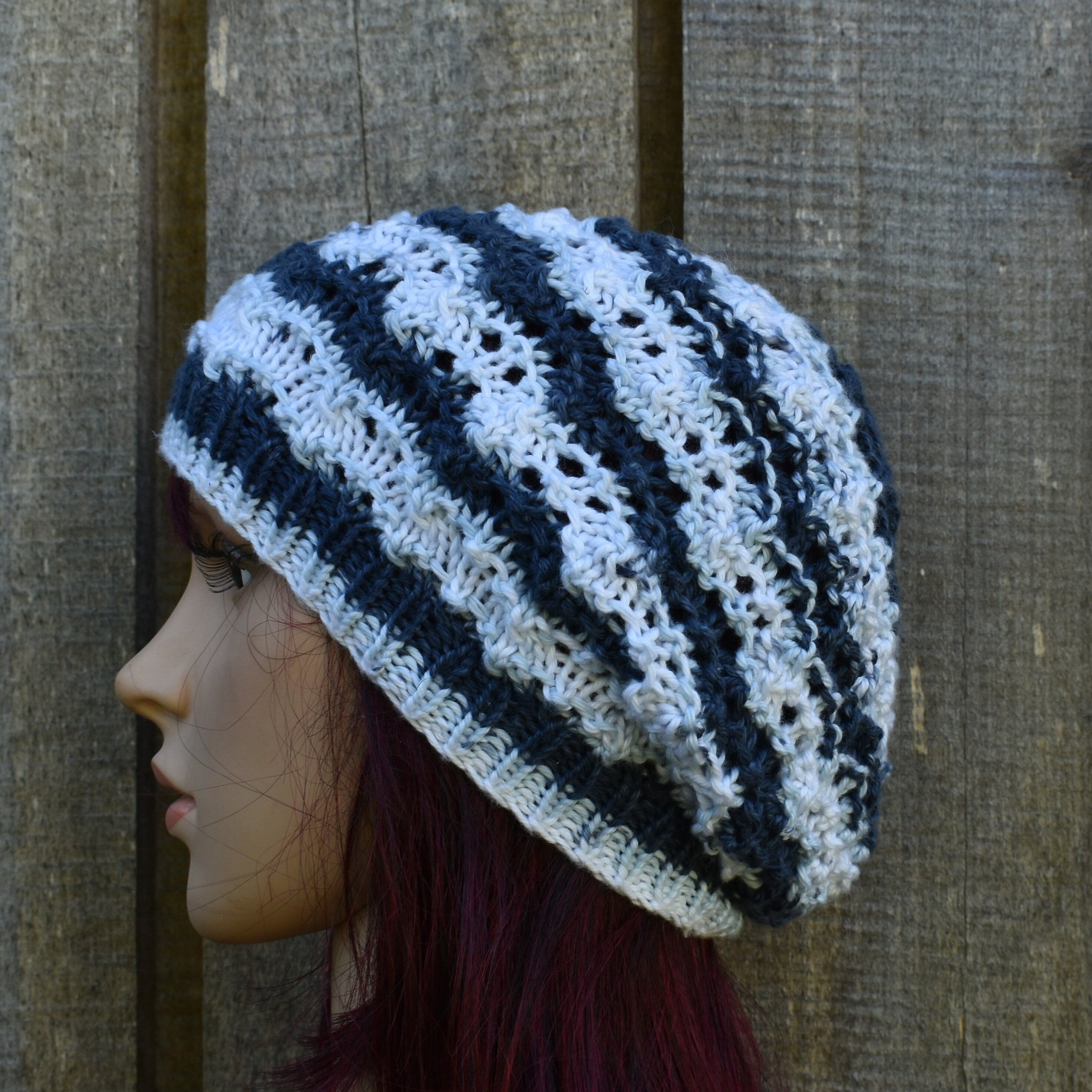 Knitted beanie with blue and white stripes on a wooden background