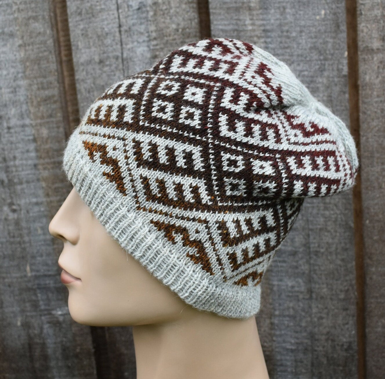 Knitted beanie with a pattern on a mannequin head against a wooden background