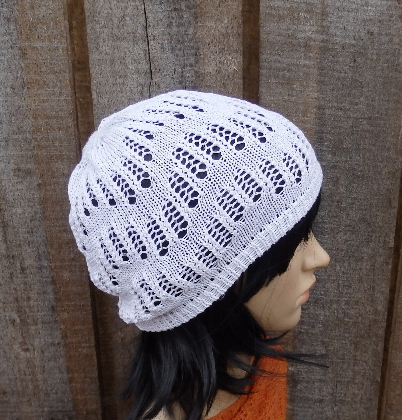 White lace knit hat on a mannequin head against a wooden background