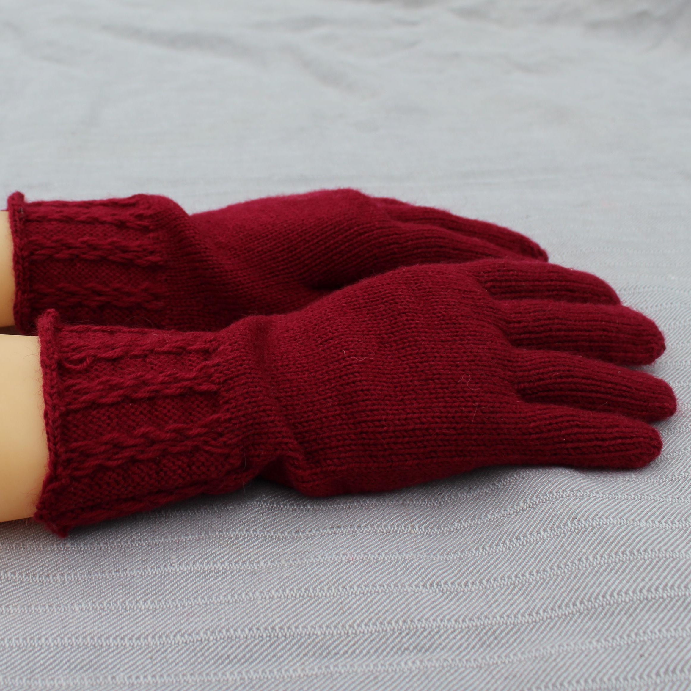 Red knitted gloves on a mannequin arm against a gray background