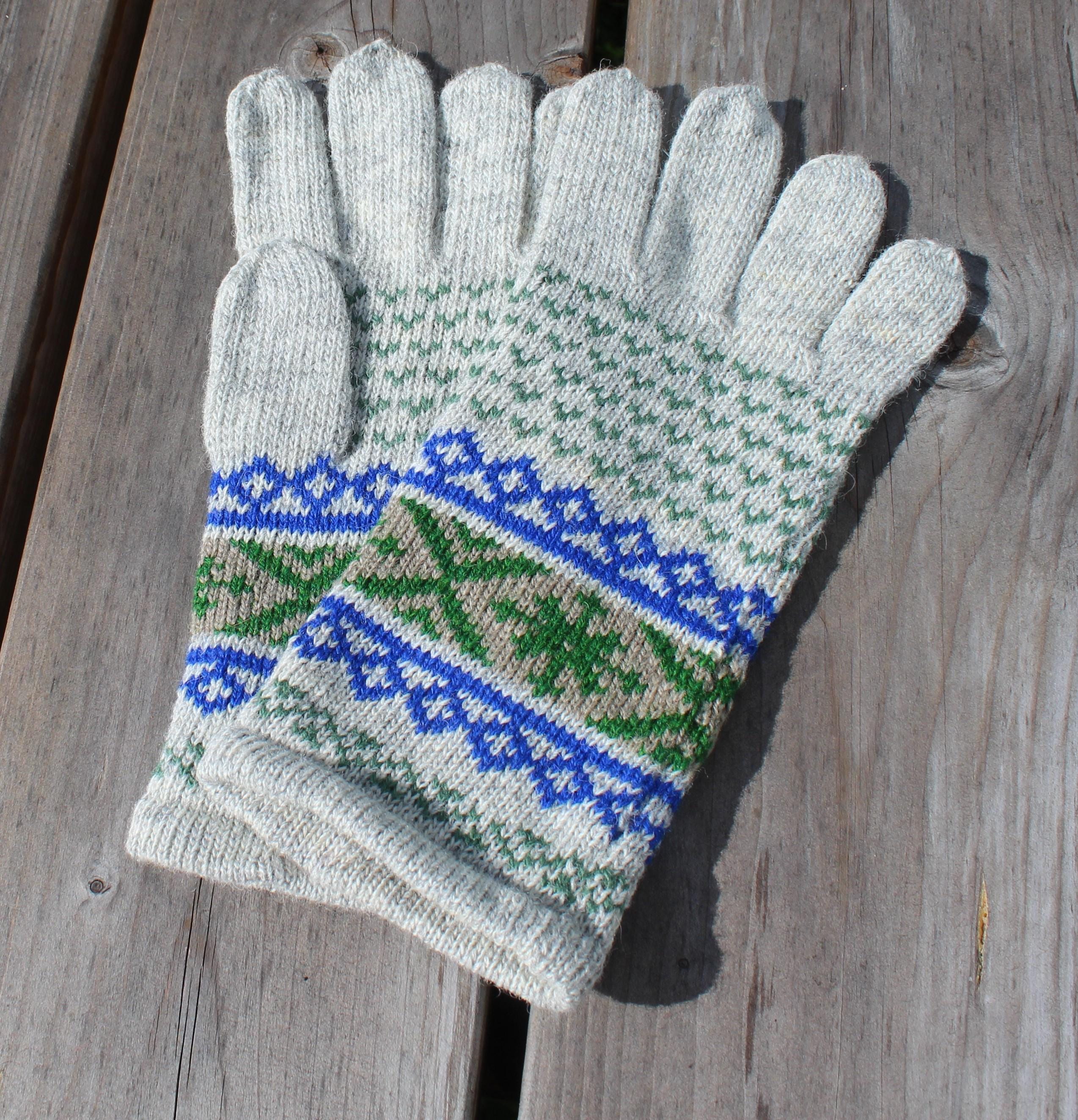 Pair of gray gloves with blue and green pattern on a wooden surface
