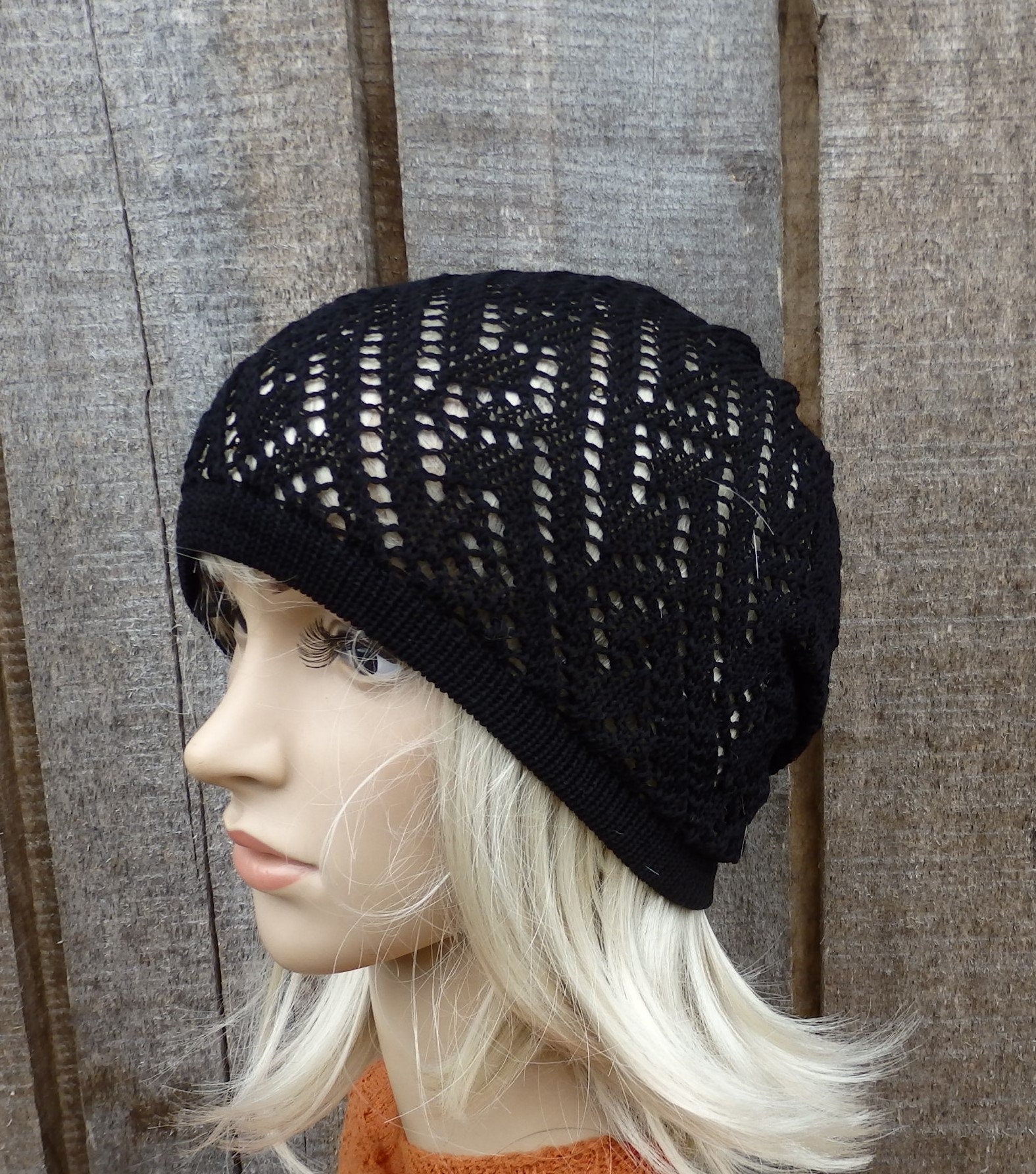 Black knit beanie on a mannequin head against a wooden background