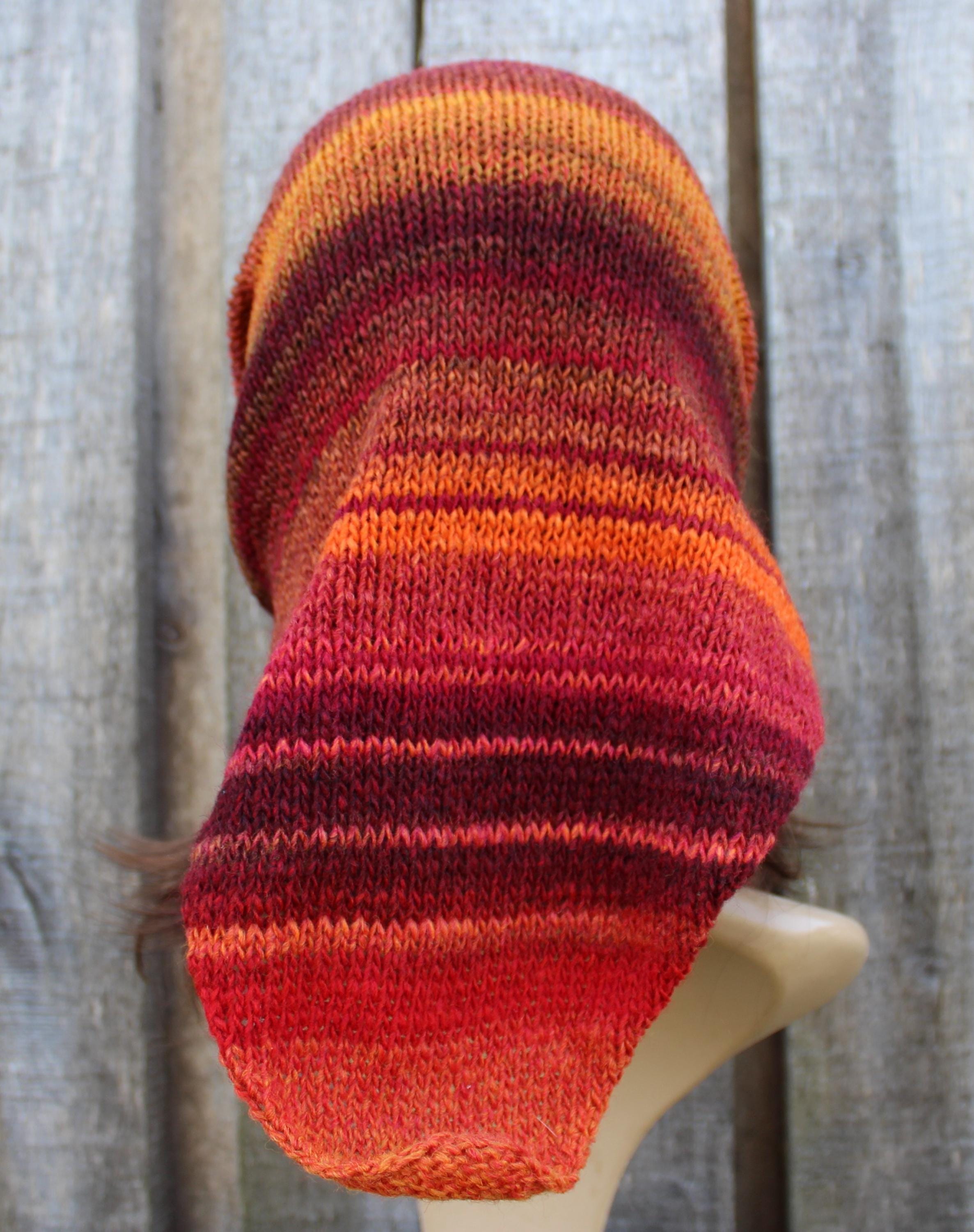Knitted scarf with red and orange stripes on a wooden mannequin against a wooden background