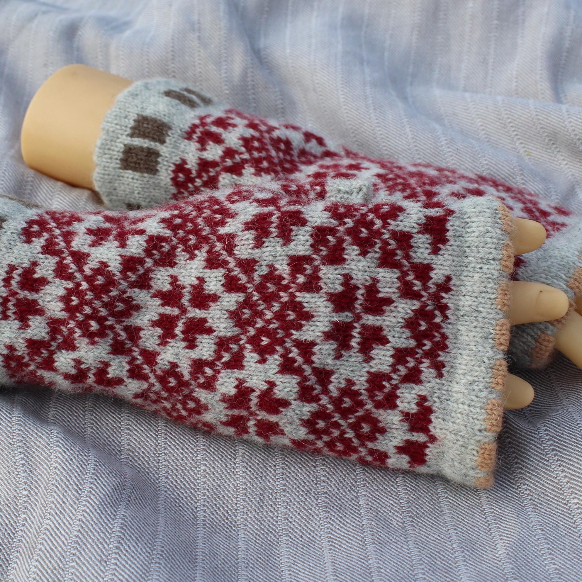 Knitted gloves with a red and white pattern on a fabric background