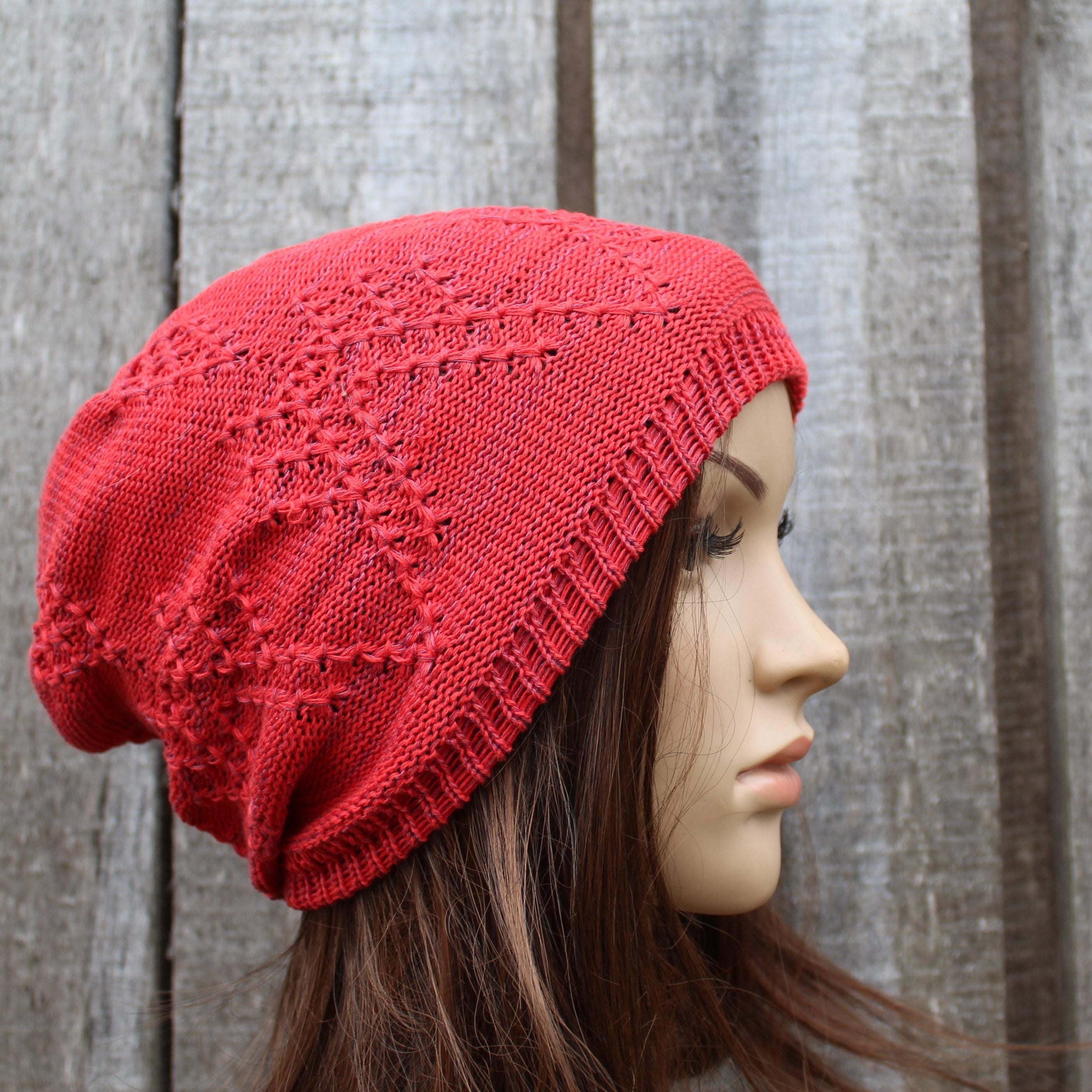 Red knitted beanie on a mannequin head against a wooden background