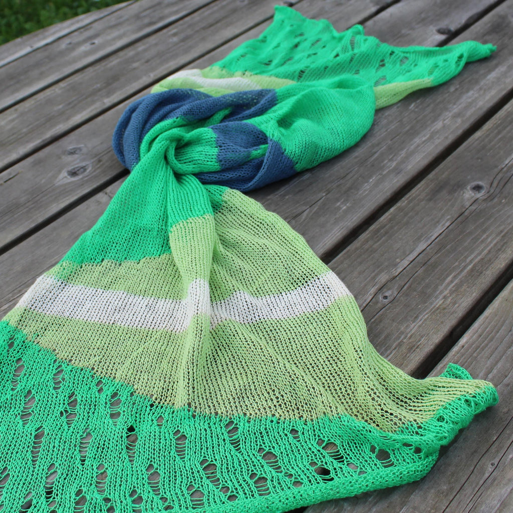 Green knitted shawl with lace details on a wooden surface