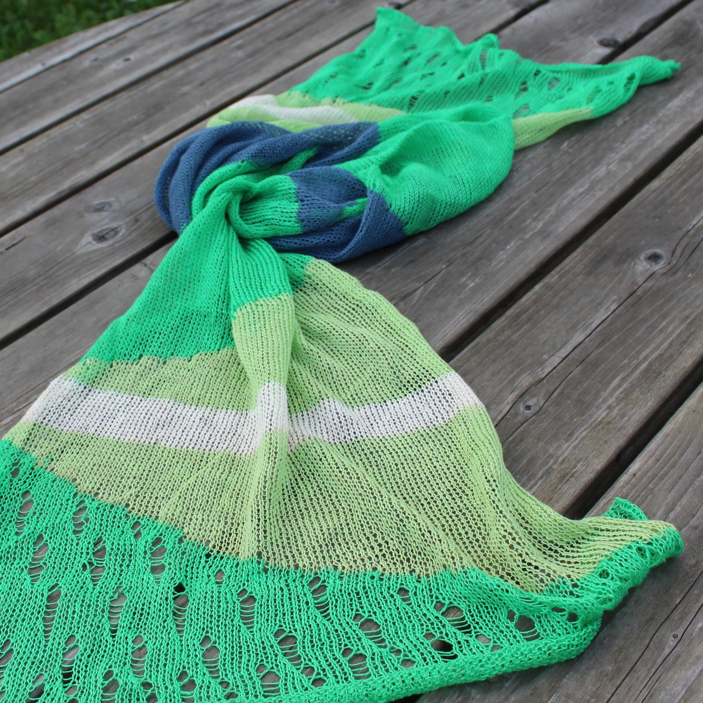 Green knitted shawl with lace details on a wooden surface