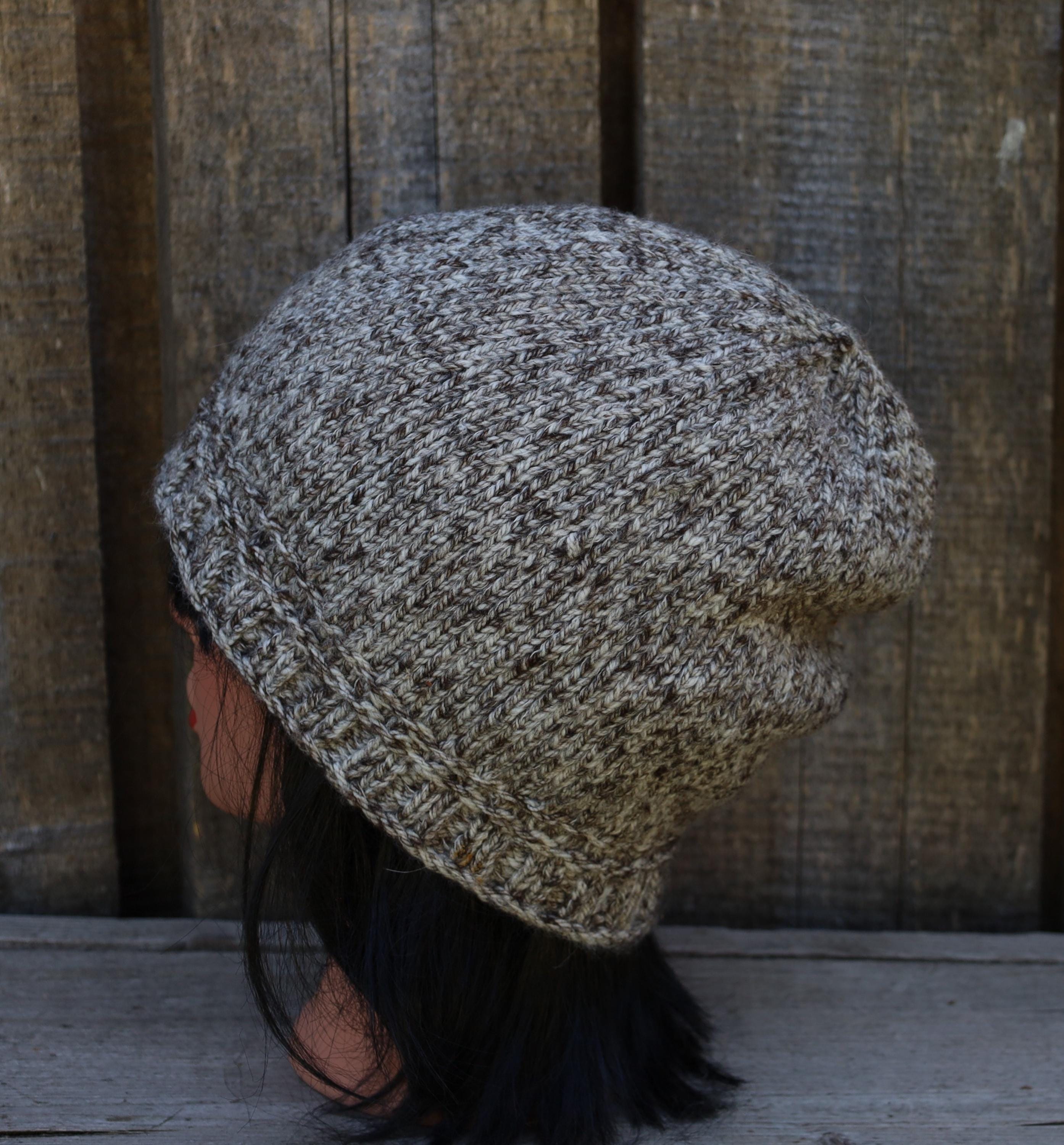 Person wearing a textured knit beanie against a wooden background