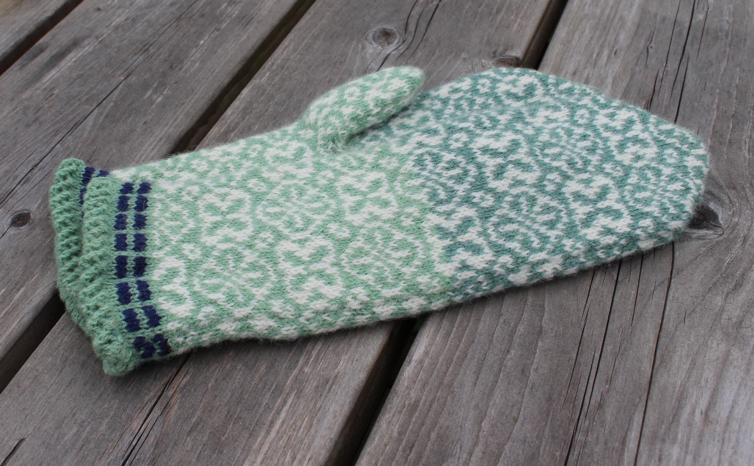 Knitted green mitten on a wooden surface