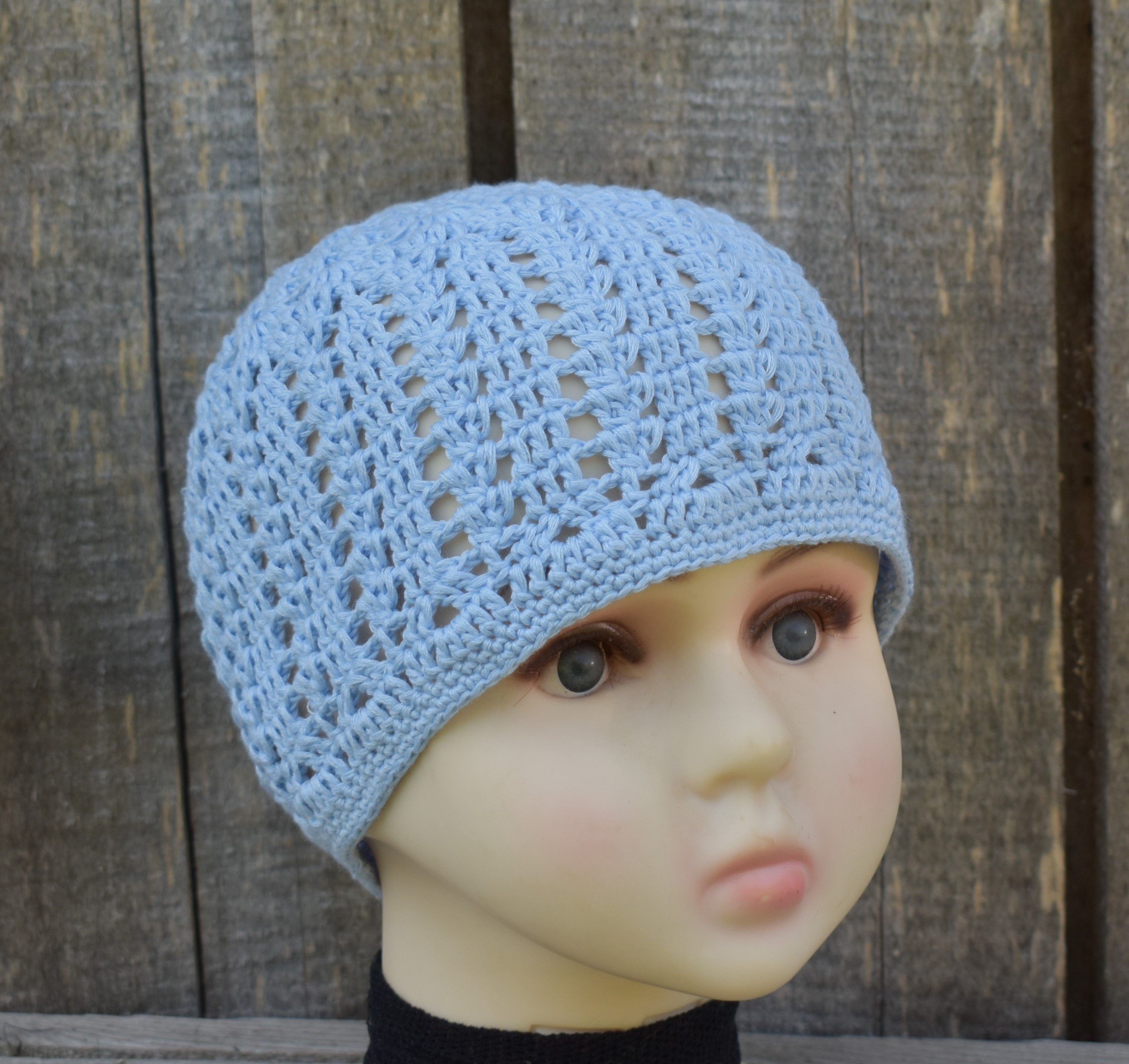 Light blue knitted beanie on a mannequin head against a wooden background