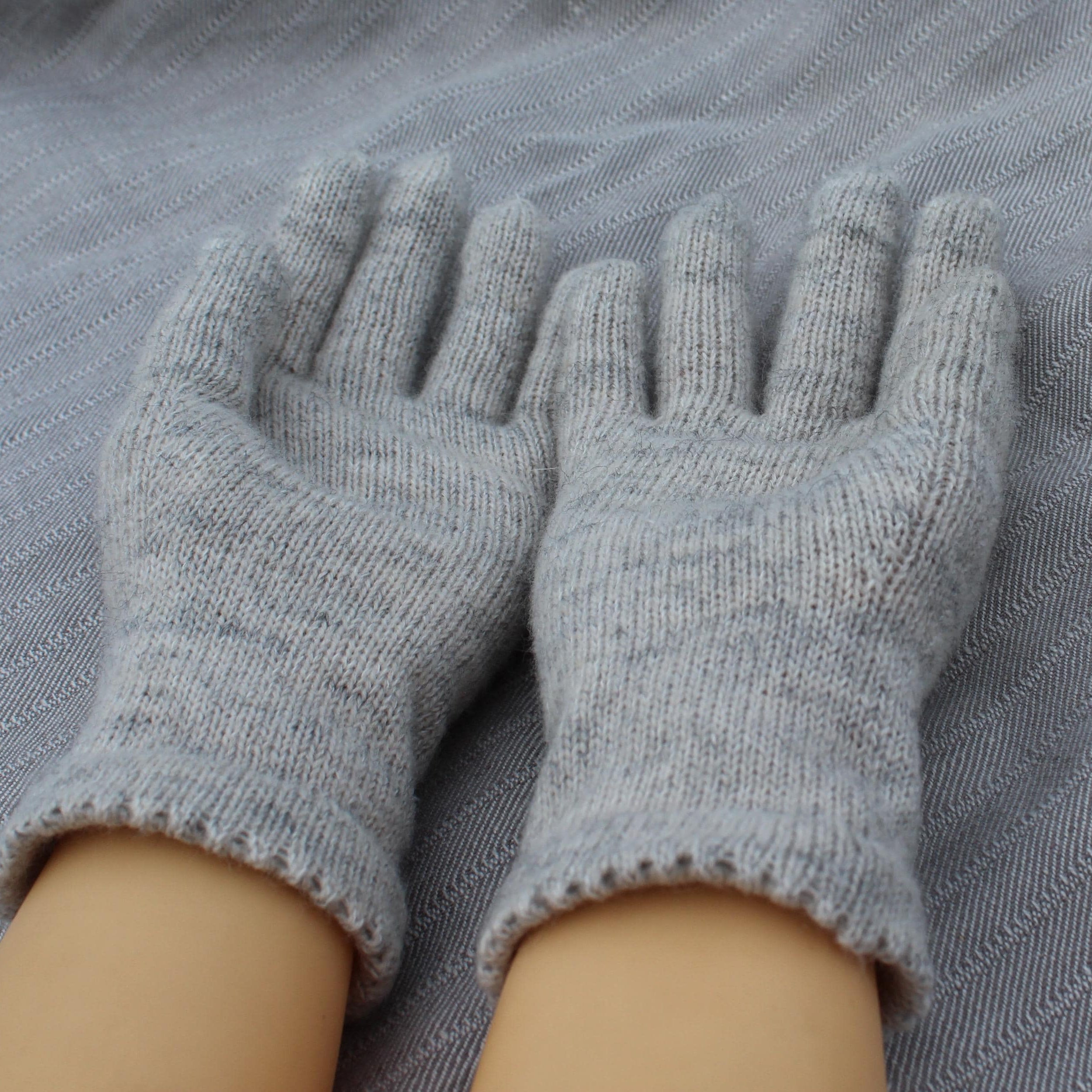 Pair of gray gloves on a textured gray surface
