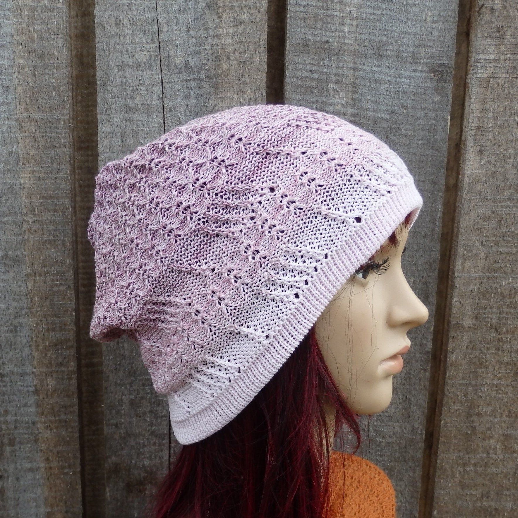 Knitted pink beanie on a mannequin head against a wooden background