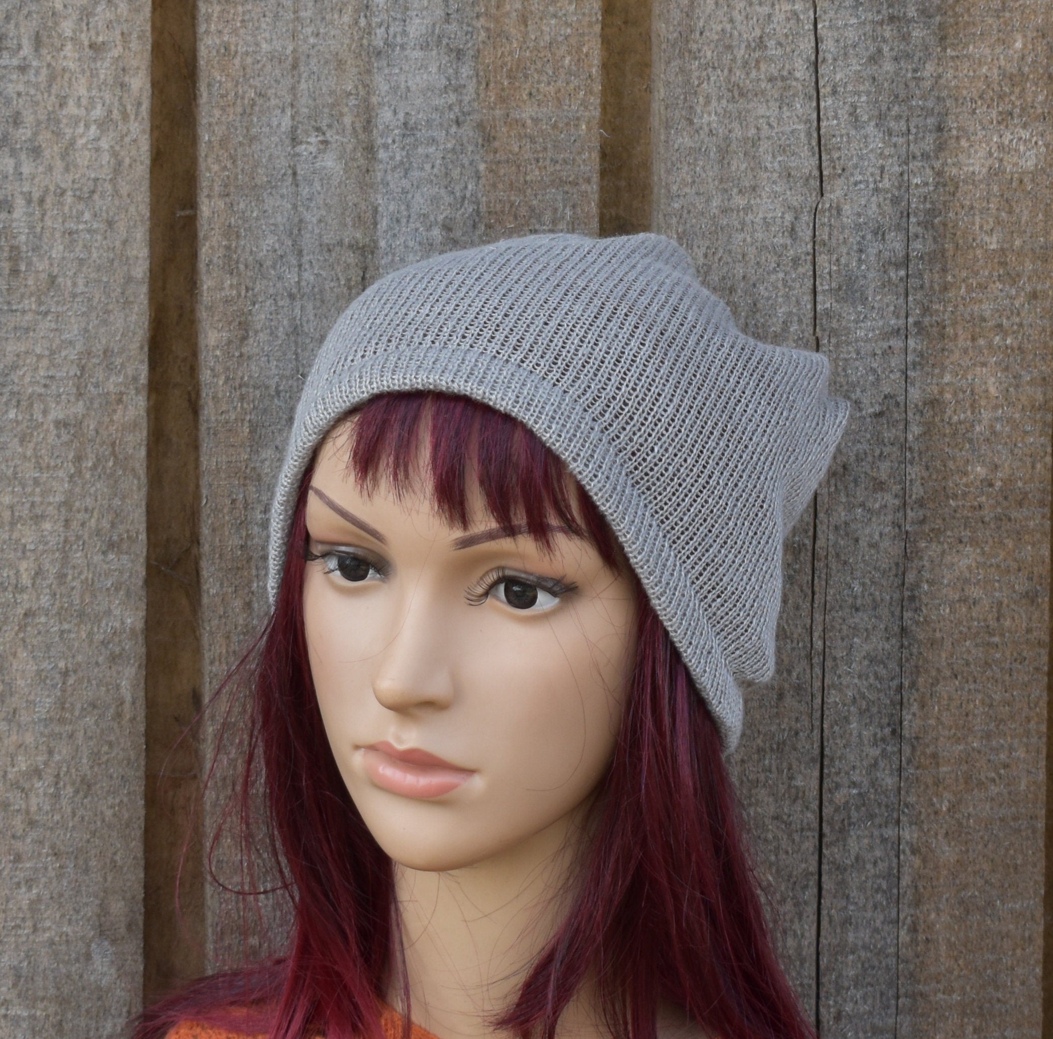 Mannequin head wearing a gray knit beanie against a wooden background