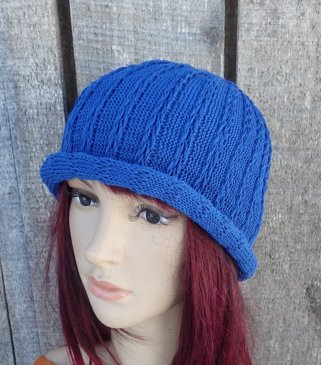 Blue knitted cap on a mannequin head against a wooden background