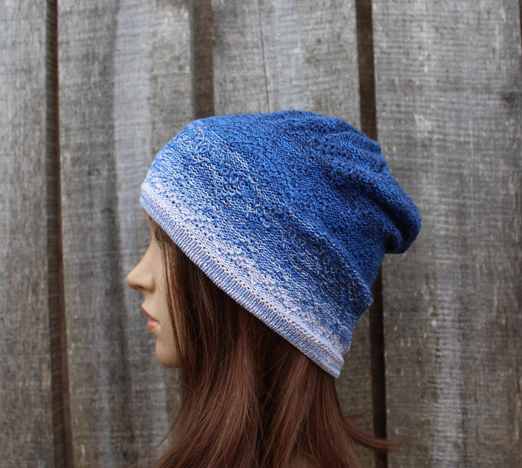 Blue knitted beanie worn by a person against a wooden fence background