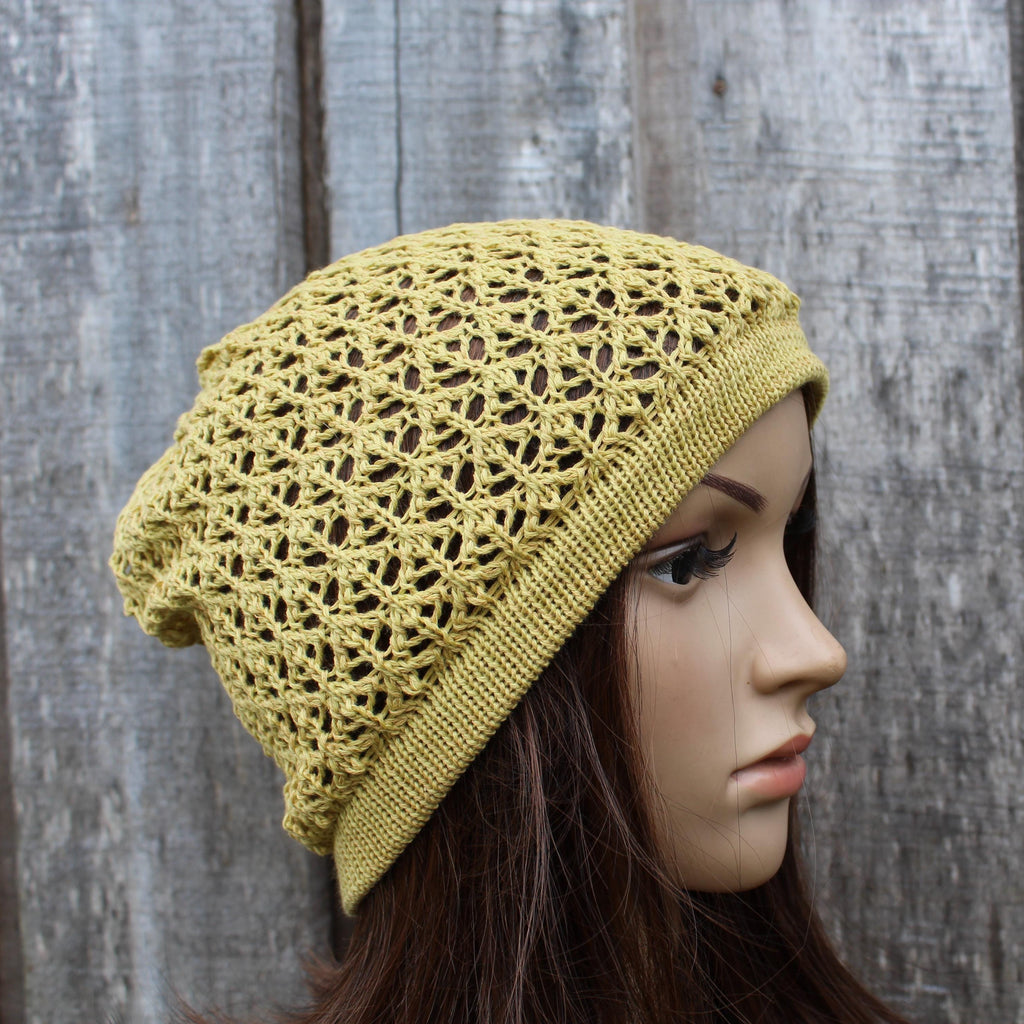 Yellow lace knit beanie on a mannequin head against a wooden background