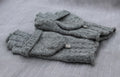 Folded gray knitted gloves on a textured surface