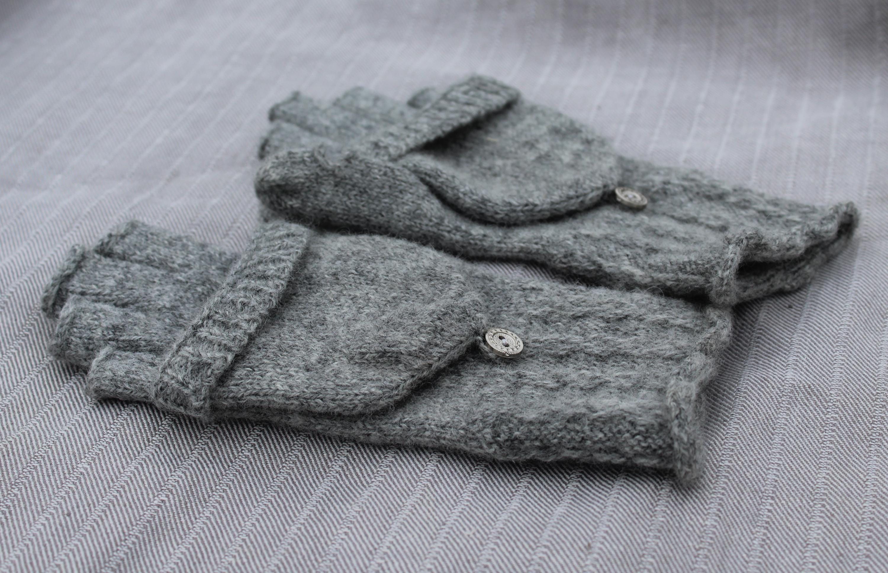 Folded gray knitted gloves on a textured surface