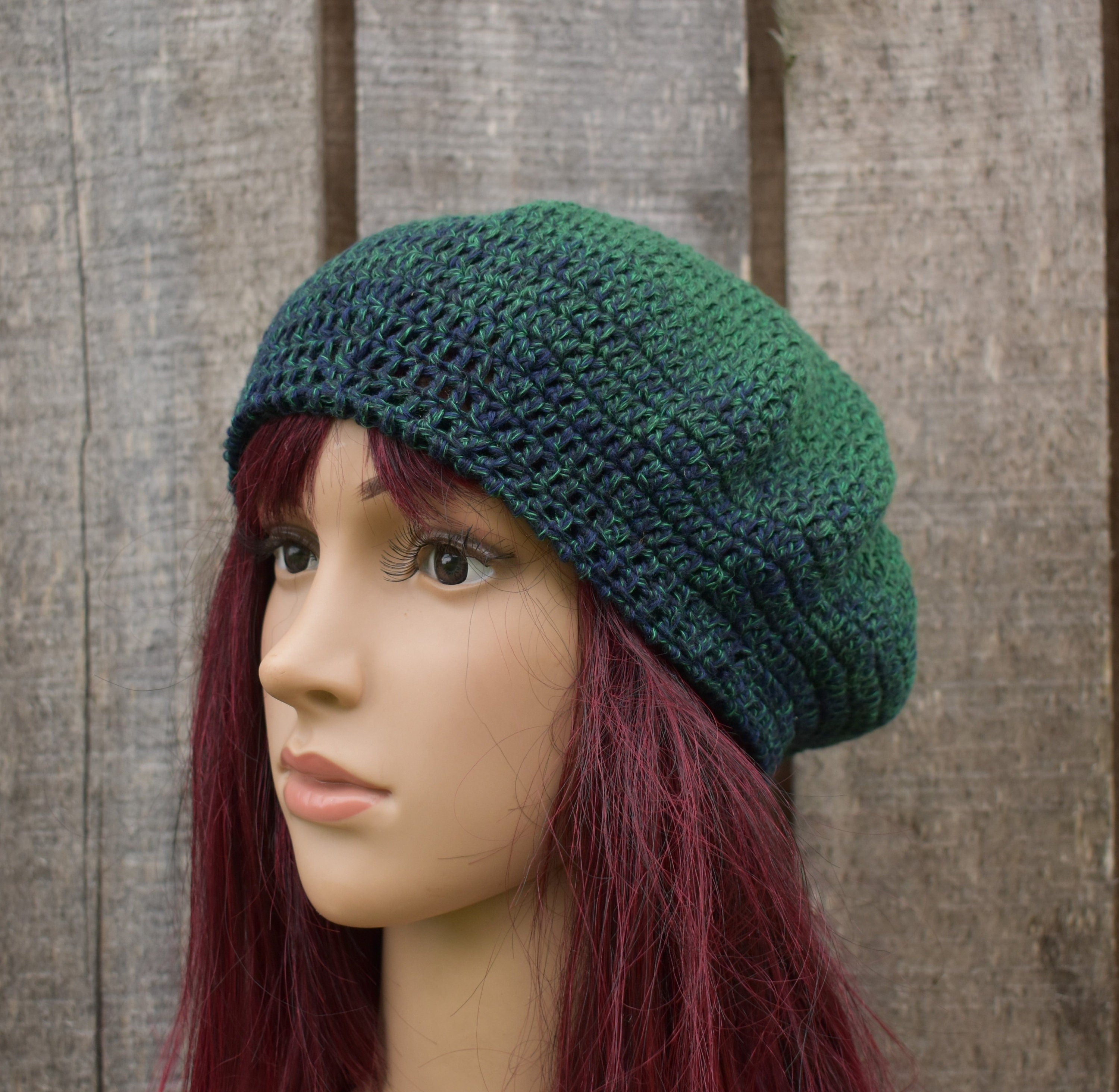 Green knitted beanie on a mannequin head against a wooden background