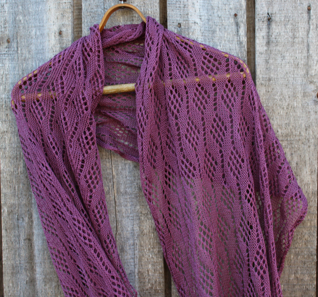 Purple knitted shawl on a wooden hanger against a wooden background
