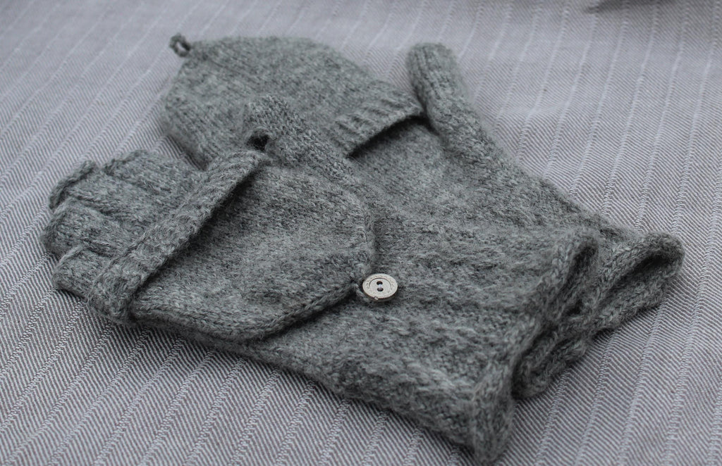 Gray gloves with buttons on a textured gray surface