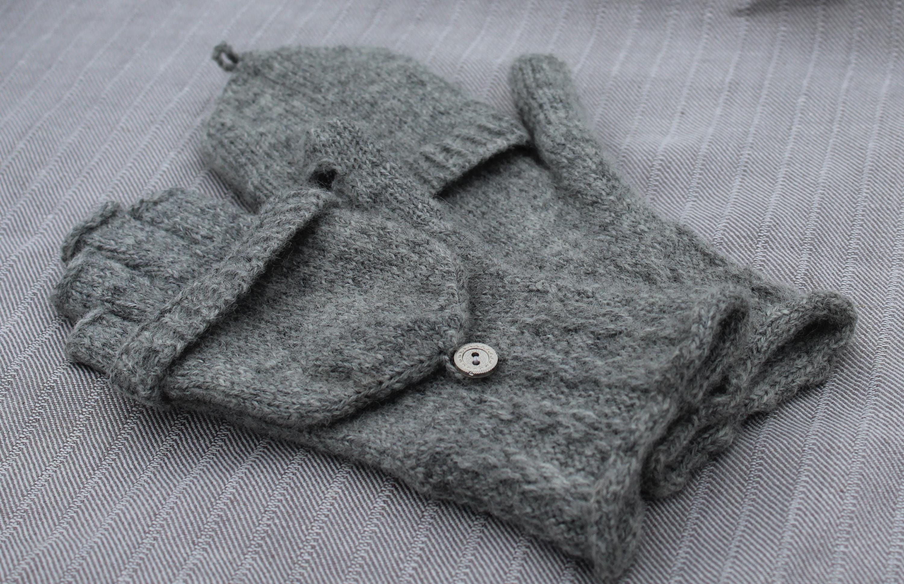 Gray gloves with buttons on a textured gray surface