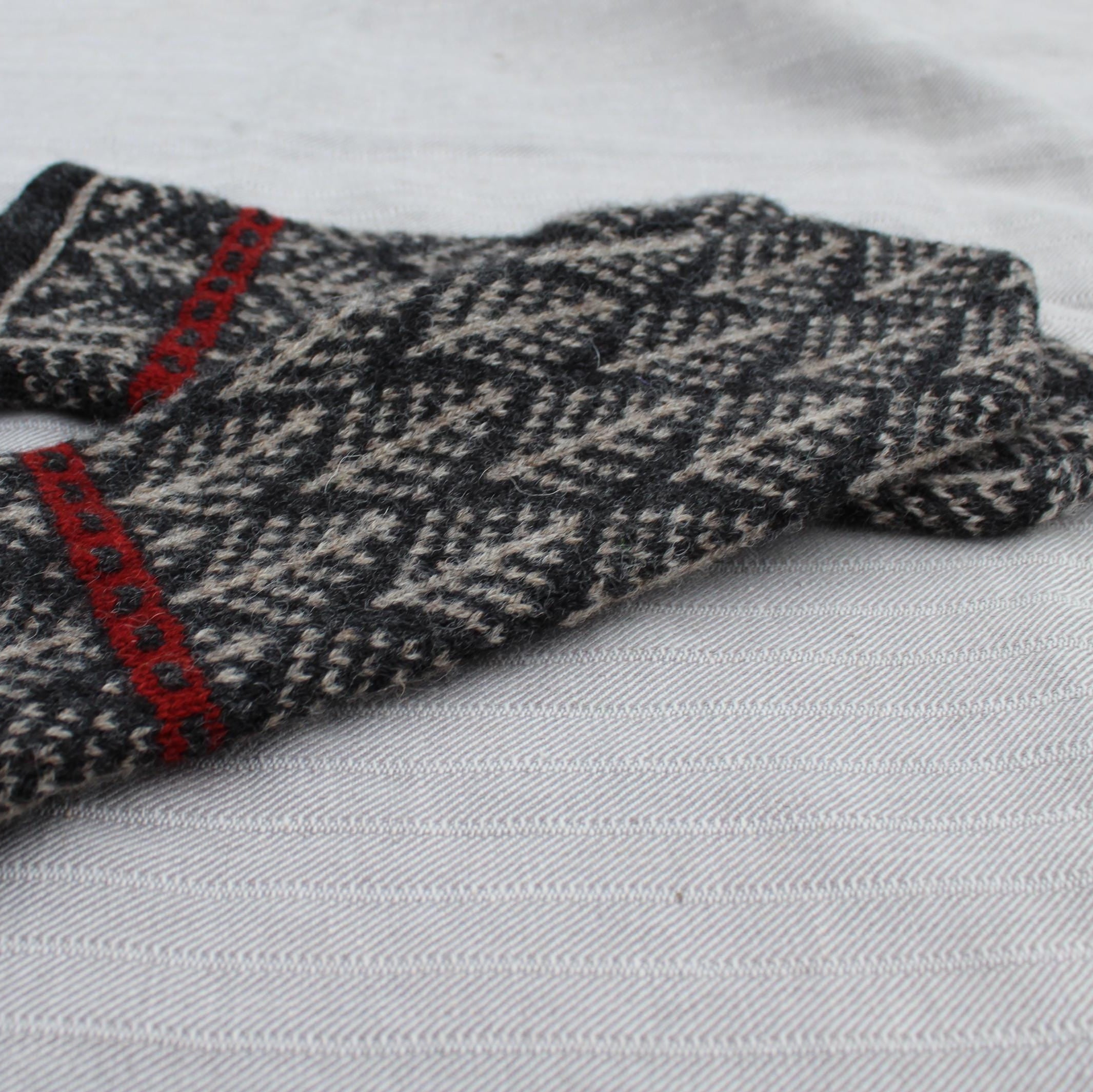 Pair of knitted gloves with a pattern on a light gray background