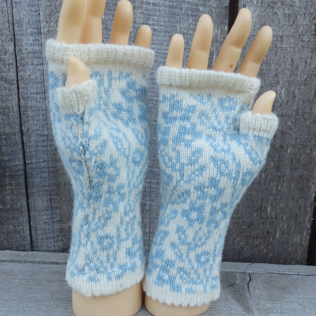 Pair of blue and white patterned fingerless gloves on a mannequin hand against a wooden background