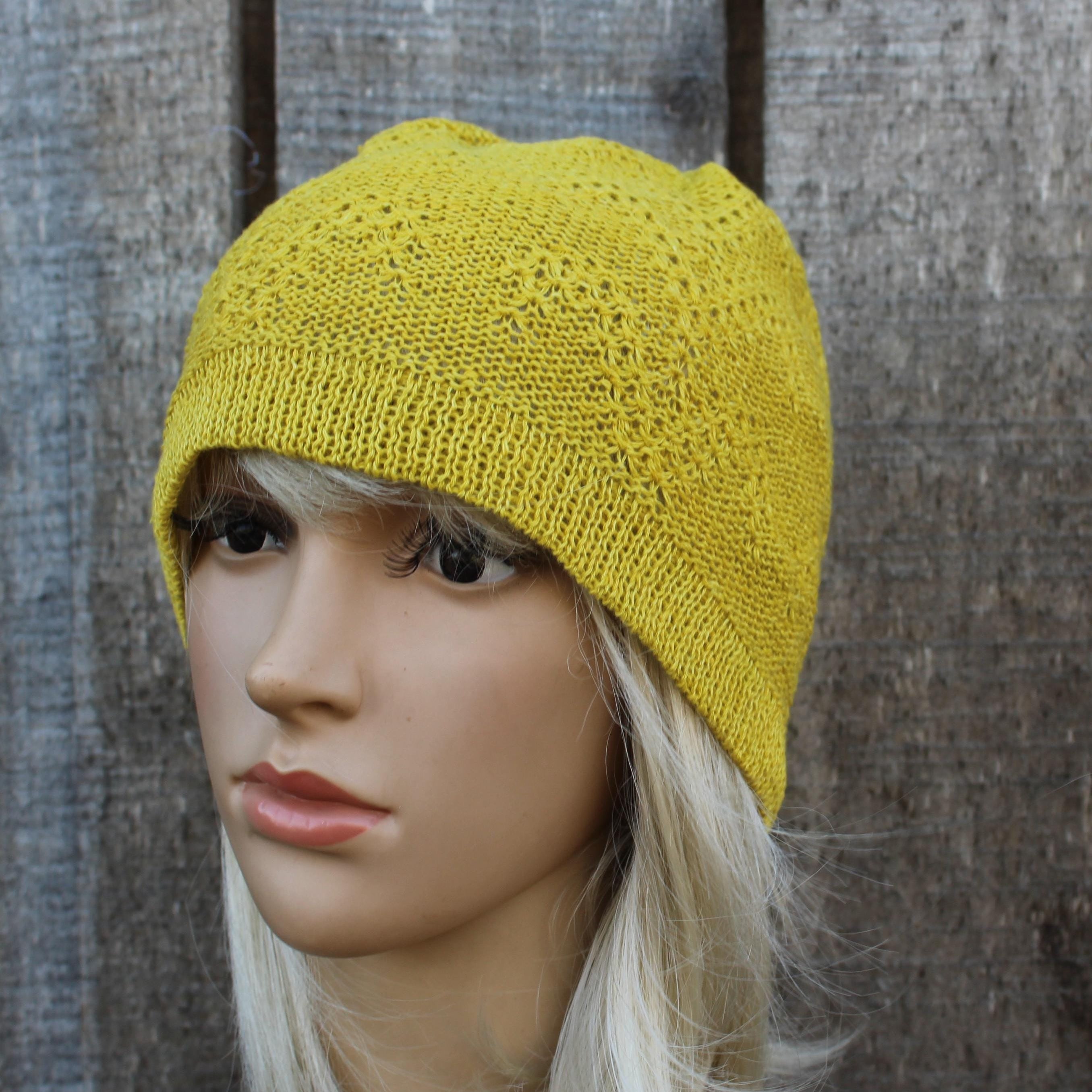 Yellow knitted beanie on a mannequin head against a wooden background